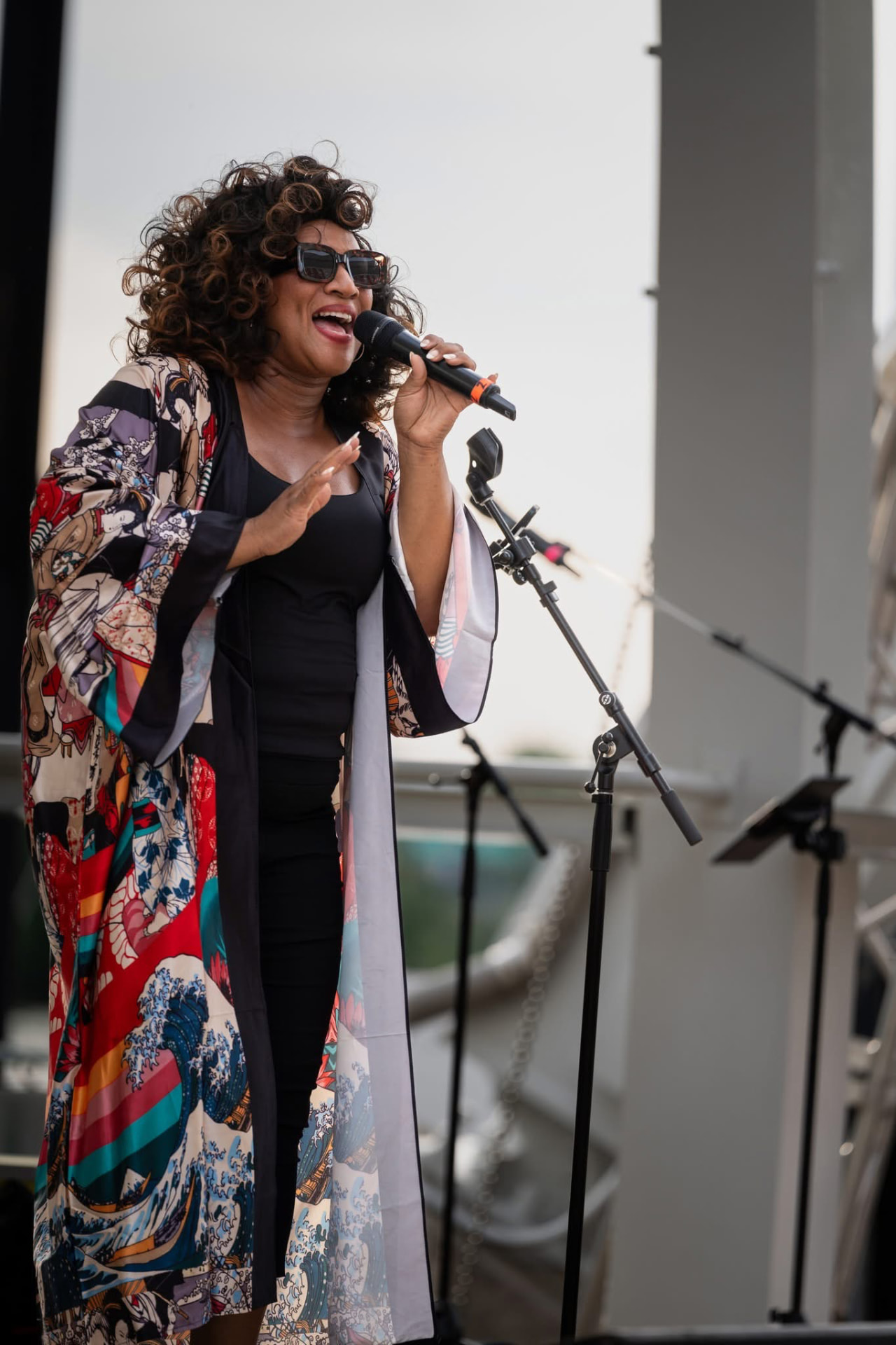 Christina Cunningham singing outdoors on a terrace stage in a printed kimono robe