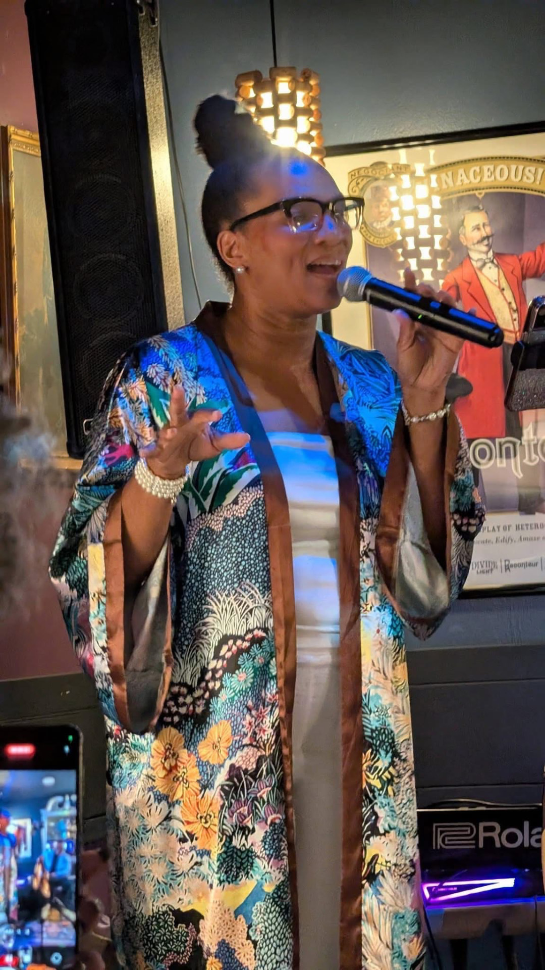 Christina Cunningham singing into a microphone in an intimate room, wearing a floral kimono